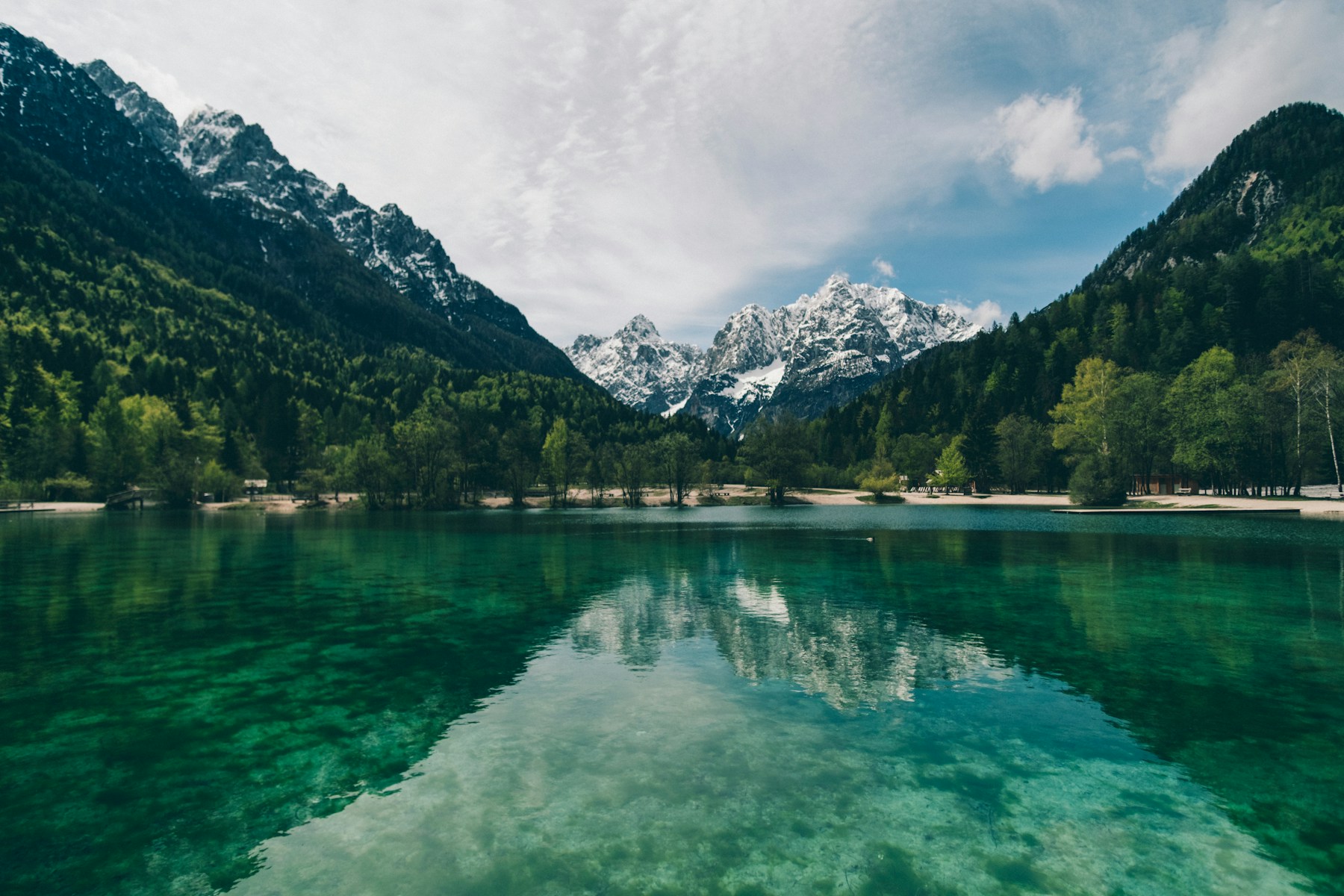 A still alpine lake reflecting forested mountains